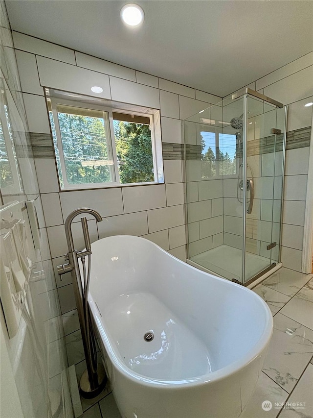 bathroom with tile walls and shower with separate bathtub