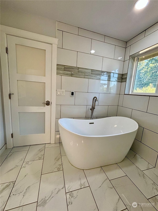 bathroom with tile walls and a bathtub