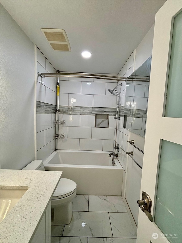 full bathroom with tiled shower / bath, vanity, and toilet