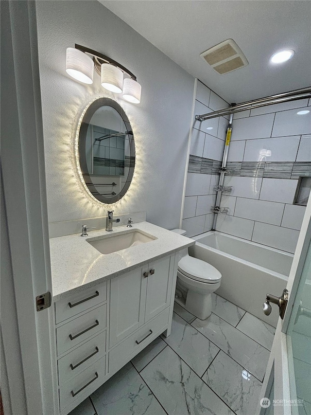 full bathroom featuring vanity, tiled shower / bath, and toilet