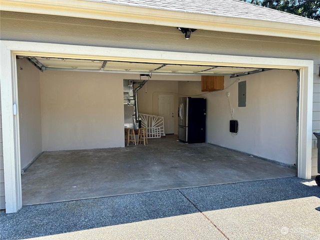 garage with electric panel and stainless steel fridge with ice dispenser