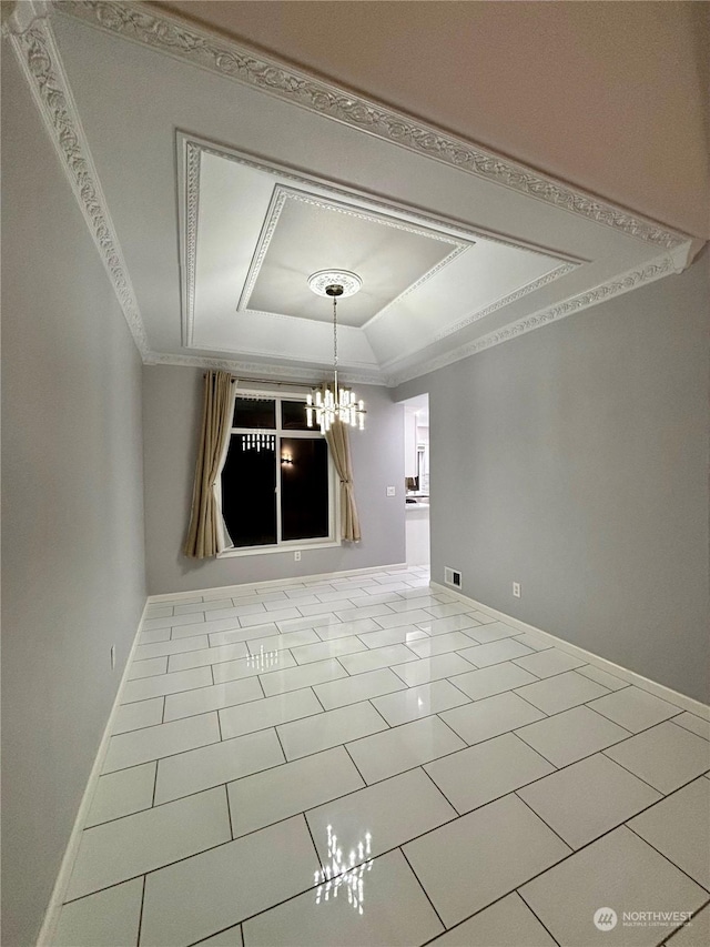 tiled spare room featuring a raised ceiling, ornamental molding, and a chandelier