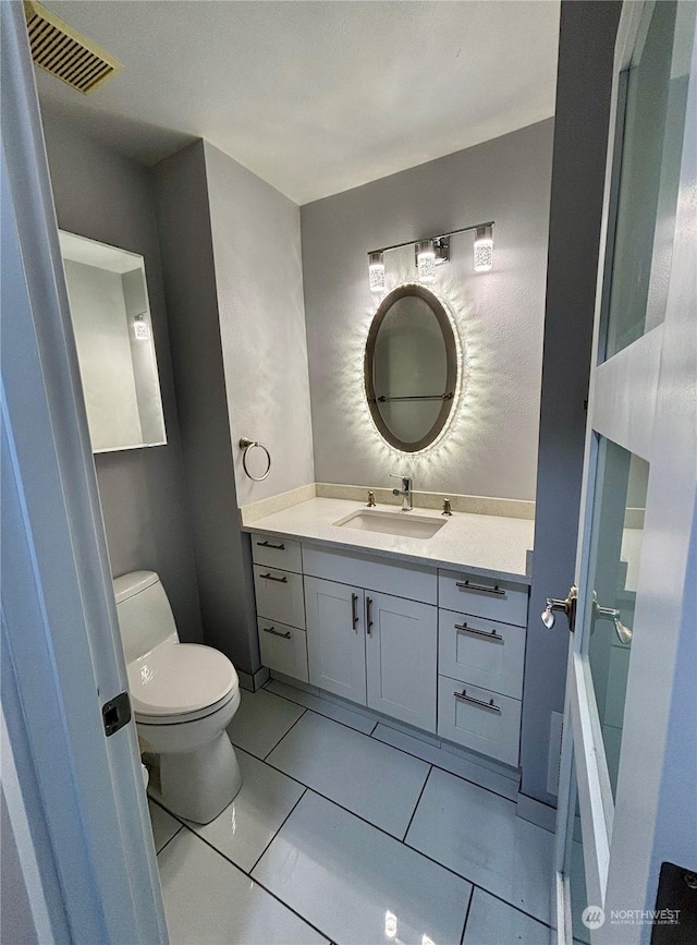 bathroom featuring vanity, tile patterned floors, and toilet