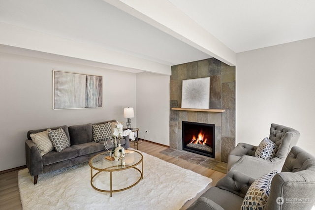 living room featuring a fireplace, beamed ceiling, and hardwood / wood-style floors