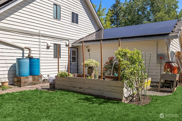 back of property featuring a yard and solar panels