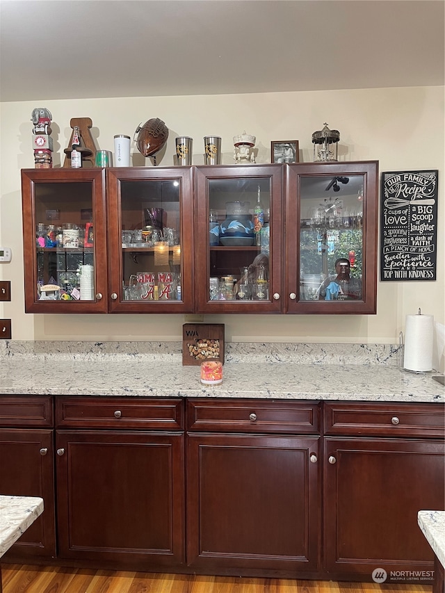 bar featuring wood-type flooring and light stone counters