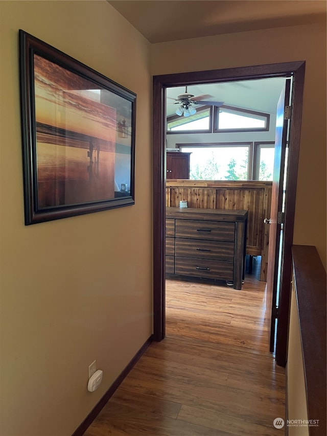 hallway with hardwood / wood-style flooring and vaulted ceiling