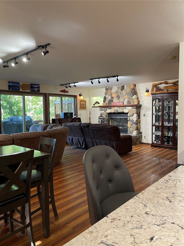 dining space featuring a fireplace, track lighting, and dark hardwood / wood-style flooring