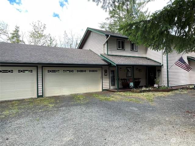 traditional home with a garage, aphalt driveway, and roof with shingles