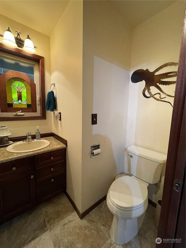 bathroom featuring vanity, toilet, and baseboards