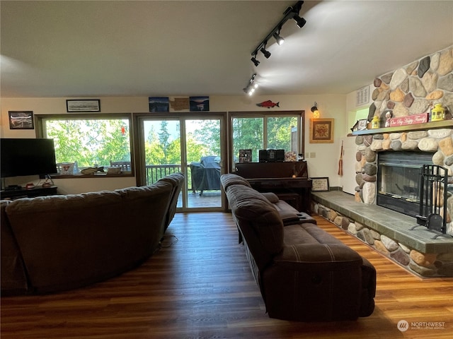 living room featuring a fireplace, track lighting, and dark wood-type flooring