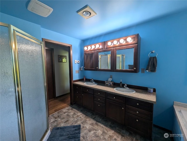 bathroom with double vanity, a shower stall, and a sink