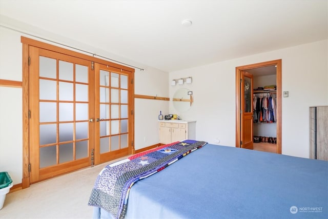 bedroom featuring a walk in closet, french doors, light colored carpet, and a closet