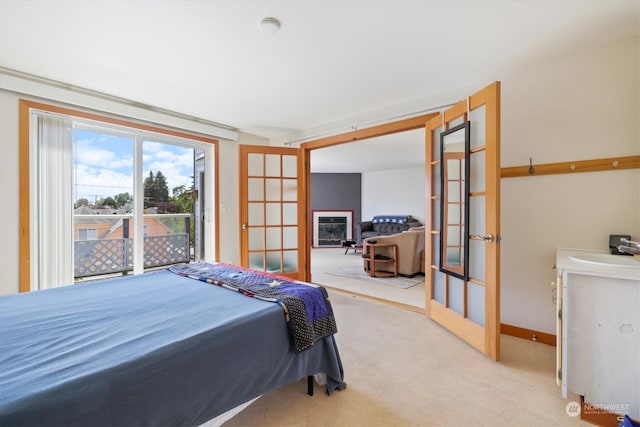 bedroom featuring sink, light colored carpet, and french doors