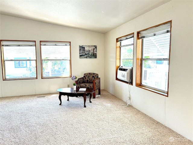 sitting room with cooling unit, vaulted ceiling, carpet, and a textured ceiling