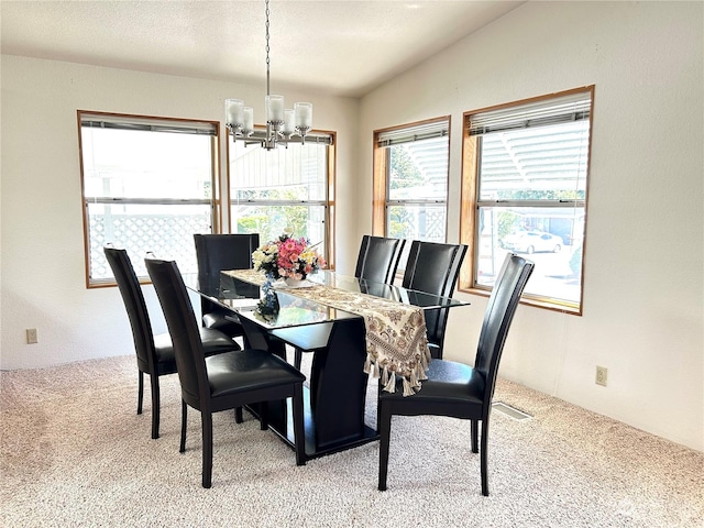 carpeted dining space featuring vaulted ceiling, a textured ceiling, and an inviting chandelier