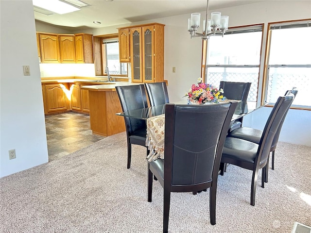 dining space featuring light colored carpet, sink, and a notable chandelier