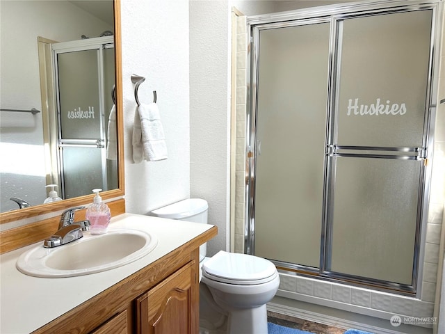 bathroom featuring vanity, a shower with shower door, and toilet