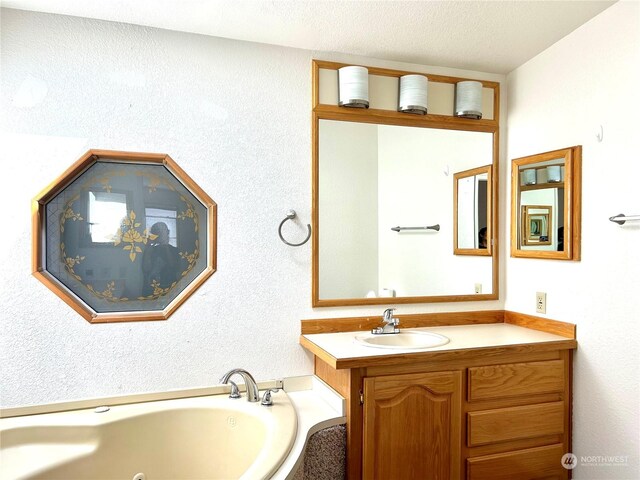 bathroom with vanity, a bathing tub, and a textured ceiling