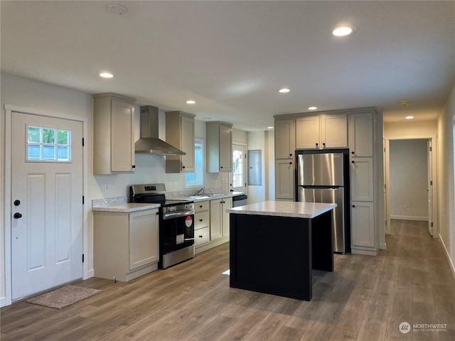 kitchen featuring appliances with stainless steel finishes, a kitchen island, gray cabinetry, and wall chimney range hood