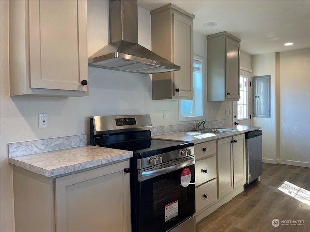 kitchen with sink, dark hardwood / wood-style floors, wall chimney range hood, and appliances with stainless steel finishes