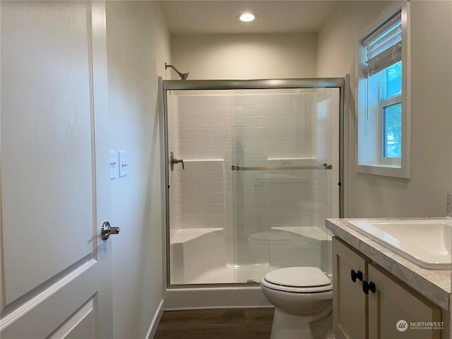 bathroom featuring vanity, wood-type flooring, a shower with shower door, and toilet