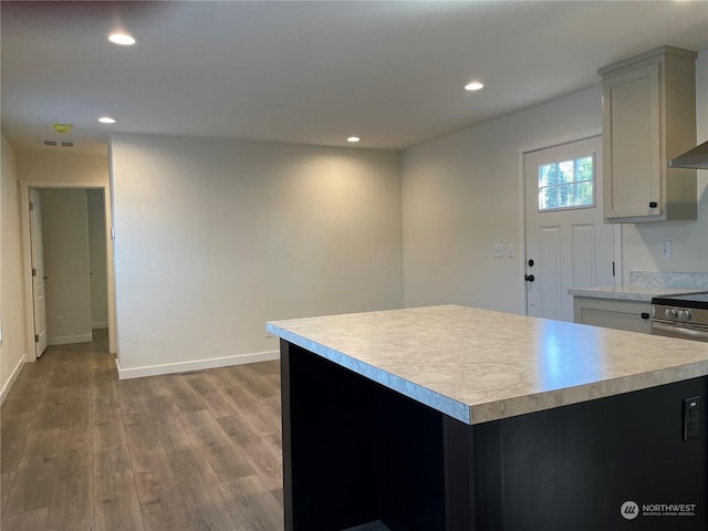 kitchen with gray cabinetry, stainless steel electric range oven, a center island, and hardwood / wood-style flooring