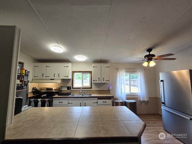 kitchen featuring sink, white cabinetry, plenty of natural light, stainless steel appliances, and tile countertops