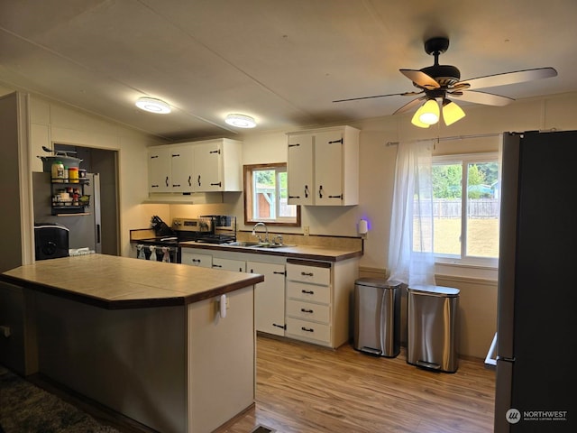 kitchen featuring sink, white cabinetry, light wood-type flooring, appliances with stainless steel finishes, and tile counters