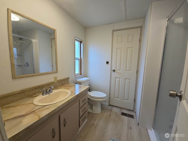 bathroom with hardwood / wood-style flooring, vanity, toilet, and a shower with door