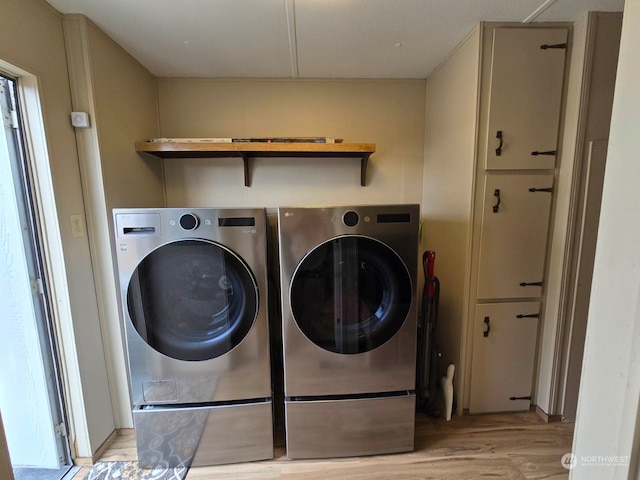 clothes washing area featuring washing machine and clothes dryer and light hardwood / wood-style flooring