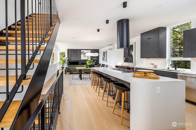 kitchen with sink, a breakfast bar, stainless steel appliances, a center island, and light wood-type flooring