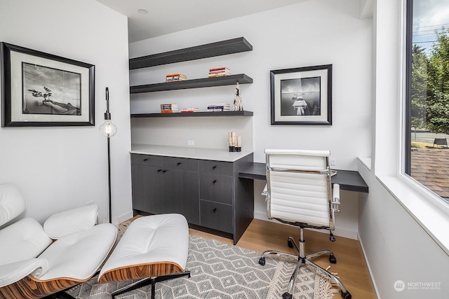 office space with a healthy amount of sunlight, built in desk, and dark hardwood / wood-style floors