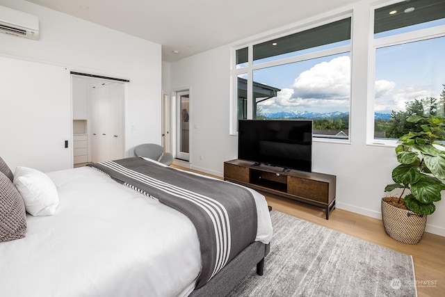 bedroom featuring a wall mounted air conditioner, a closet, and light wood-type flooring