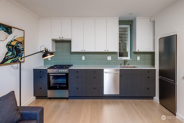 kitchen featuring white cabinetry, stainless steel appliances, sink, and light wood-type flooring