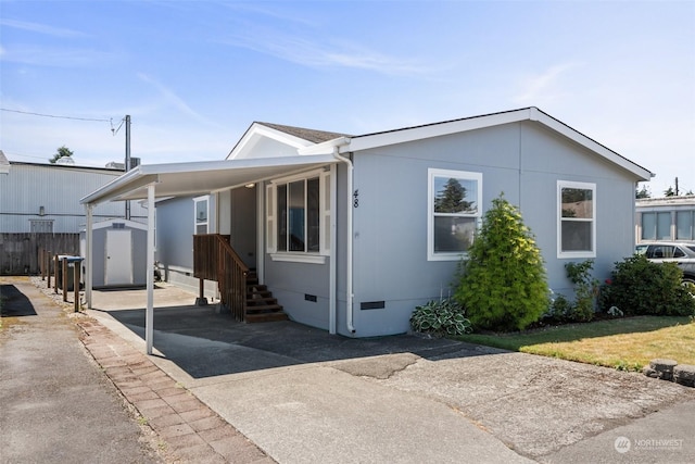 manufactured / mobile home featuring an outbuilding, driveway, crawl space, a carport, and a storage unit