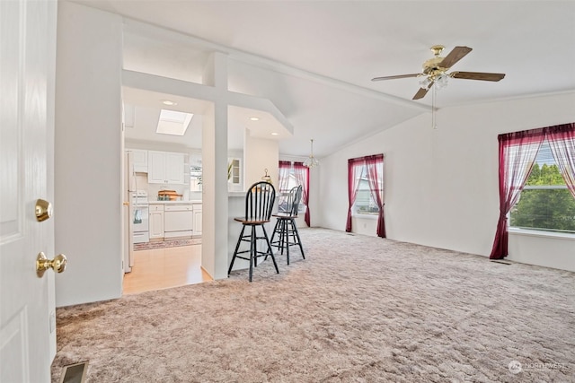 interior space with vaulted ceiling with skylight, visible vents, a wealth of natural light, and light colored carpet