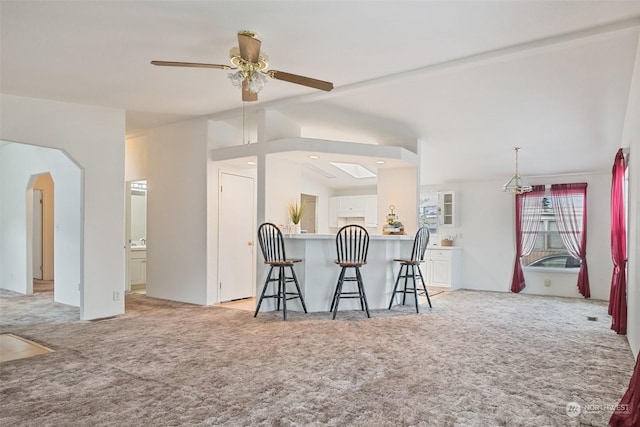 kitchen with light carpet, white cabinets, a peninsula, and a breakfast bar area