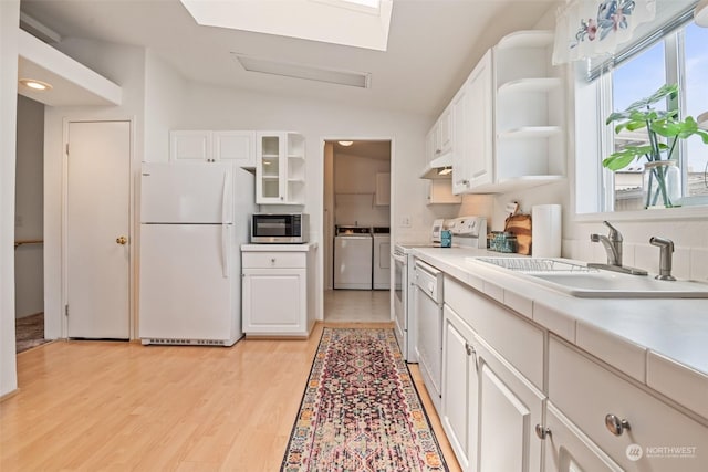 kitchen with white appliances, light countertops, washing machine and dryer, white cabinetry, and a sink