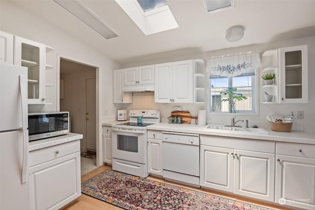 kitchen with glass insert cabinets, white appliances, white cabinets, and a sink