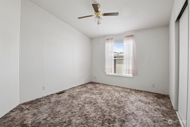 empty room with carpet floors, visible vents, and a ceiling fan