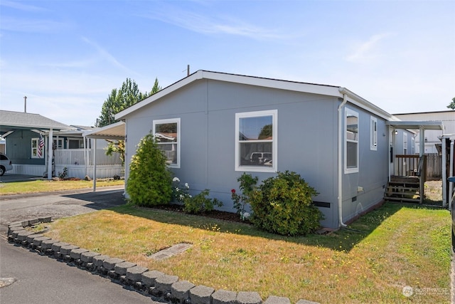 view of side of home featuring crawl space, a yard, and driveway