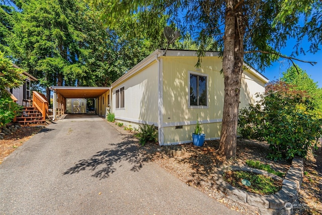 view of home's exterior featuring an attached carport, crawl space, and driveway