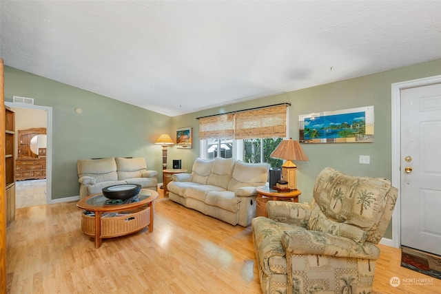 living room with lofted ceiling, a textured ceiling, wood finished floors, visible vents, and baseboards