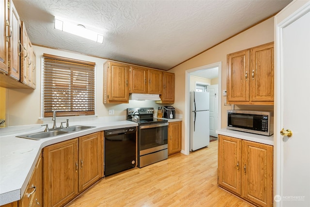 kitchen with light wood-style flooring, stainless steel appliances, light countertops, under cabinet range hood, and a sink