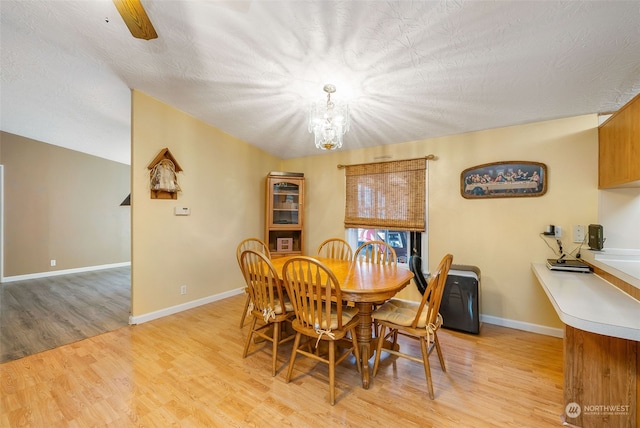 dining room with a textured ceiling, light wood-style flooring, and baseboards