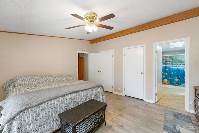 bedroom featuring crown molding, visible vents, a textured ceiling, light wood-type flooring, and baseboards