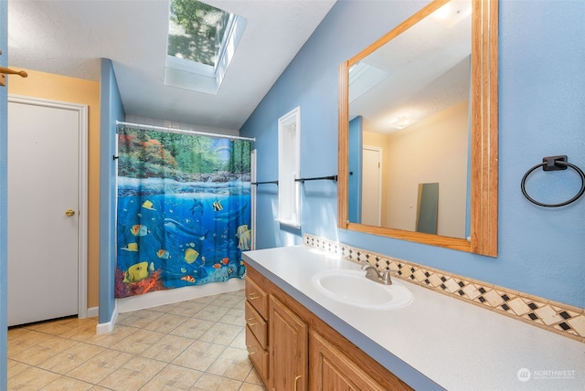 full bathroom with vaulted ceiling with skylight, curtained shower, vanity, and tile patterned floors