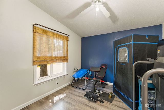 workout room featuring lofted ceiling, ceiling fan, a textured ceiling, wood finished floors, and baseboards