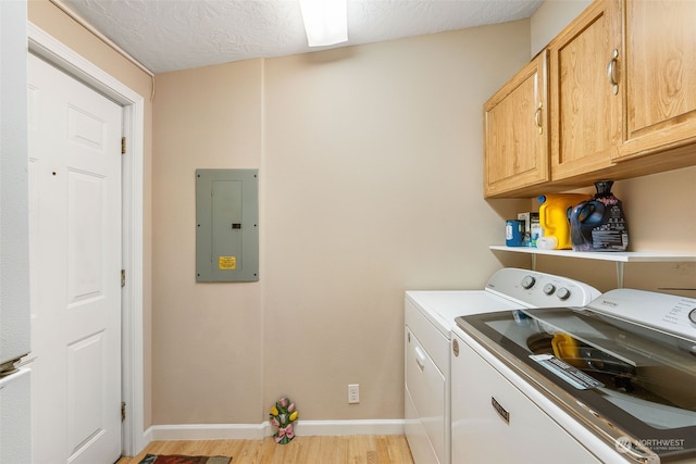 laundry room with cabinet space, electric panel, baseboards, light wood-style flooring, and independent washer and dryer